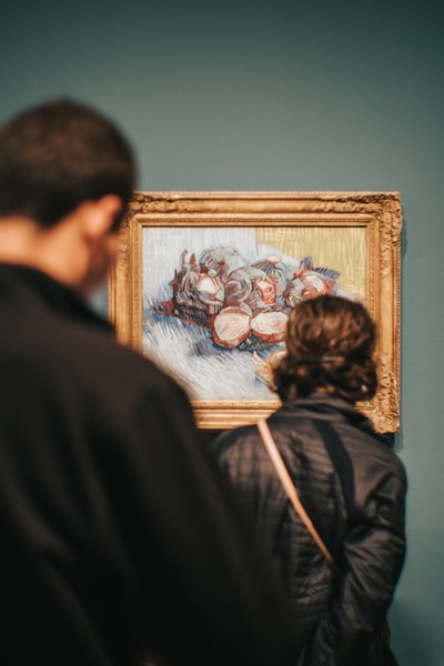 兩個人站著看文森特·梵高的《紅捲心菜和洋蔥的靜物畫》
